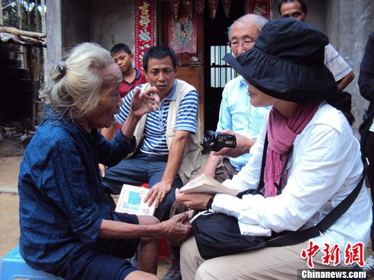 日本“海南島近代史研究會”創(chuàng)始人佐藤正人第22次到海南島調(diào)查日本侵瓊史。圖為在保亭黎族苗族自治縣南林鄉(xiāng)羅葵村，金靜美握著86歲老人林亞金的手。中新社發(fā) 張茜翼 攝