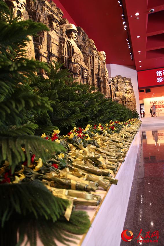 紀(jì)念館門(mén)廳的《銅墻鐵壁》雕塑墻，和人們獻(xiàn)上的花。邱越攝